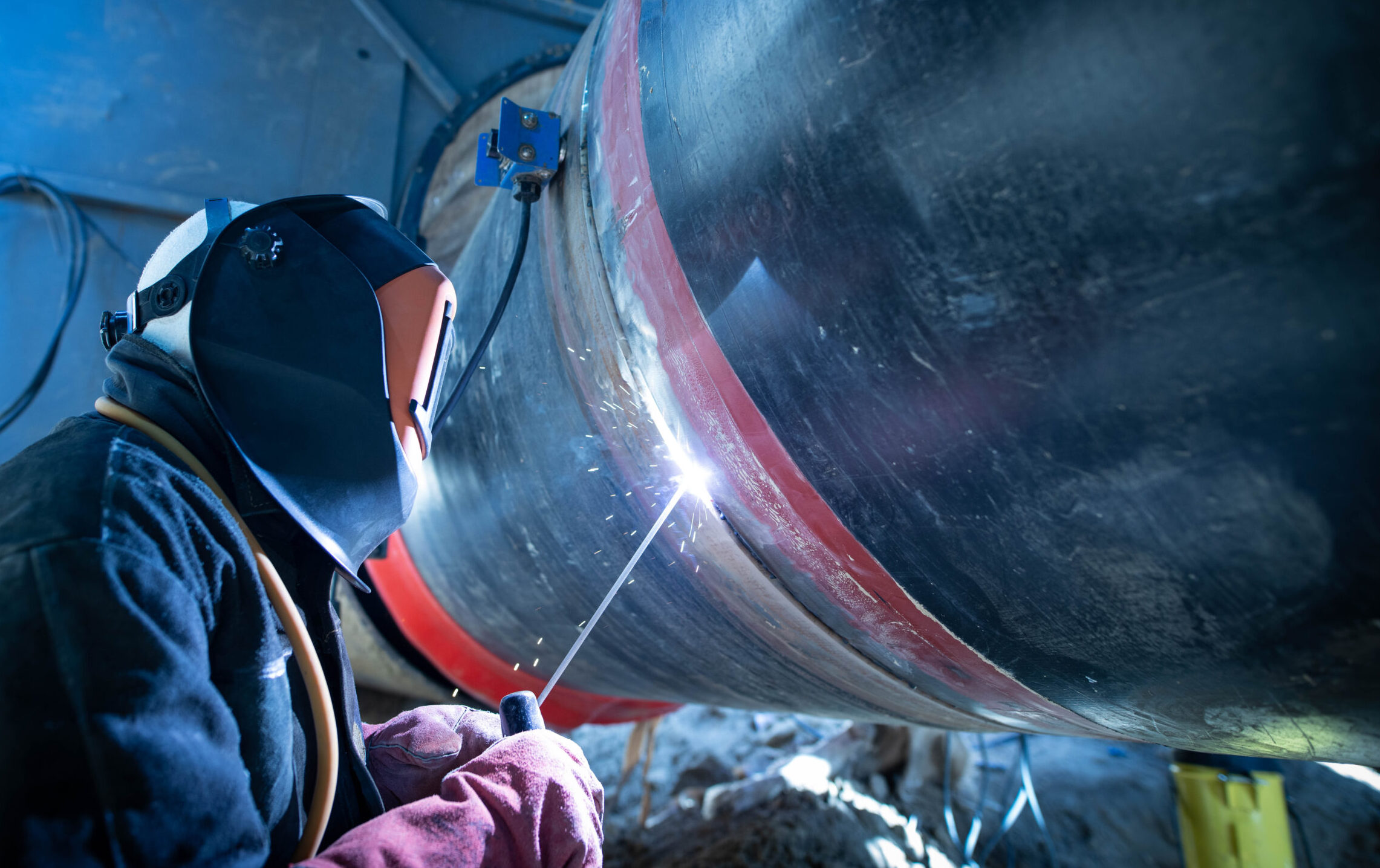 Professional welder welding pipe on a pipeline construction.